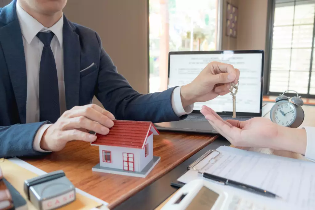 Realtor sitting at a desk handing over keys